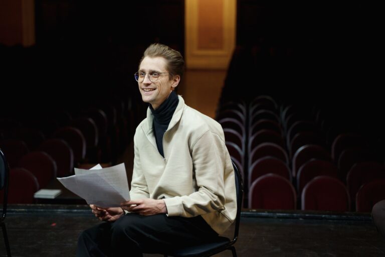 Smiling actor rehearsing a script in an empty theater
